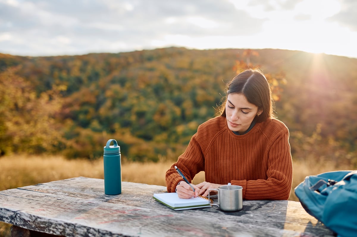 Mujer escribiendo en su diario con elementos naturales